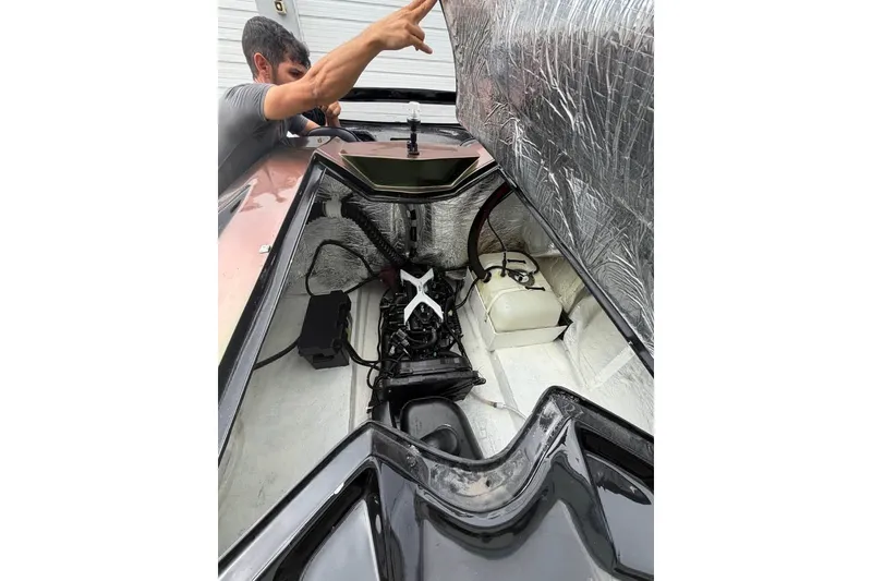 Slide: The Image of Un homme pointe vers le compartiment moteur d'un JetCar Watersports Car de 2026. - 15