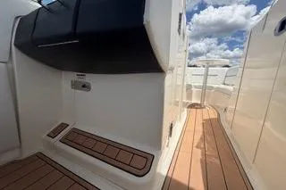 Slide: The Image of 2007 Sea Ray SLX 250 boat interior with teak flooring and white seating under a blue sky. - 63