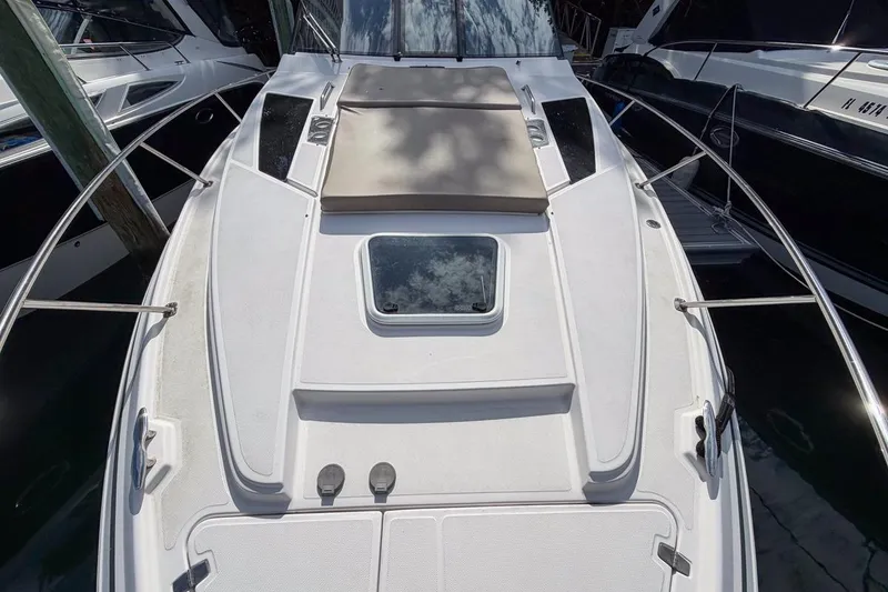 Slide: The Image of 2015 Regal 38 Express boat deck with sunpad and hatch, docked between other boats. - 33