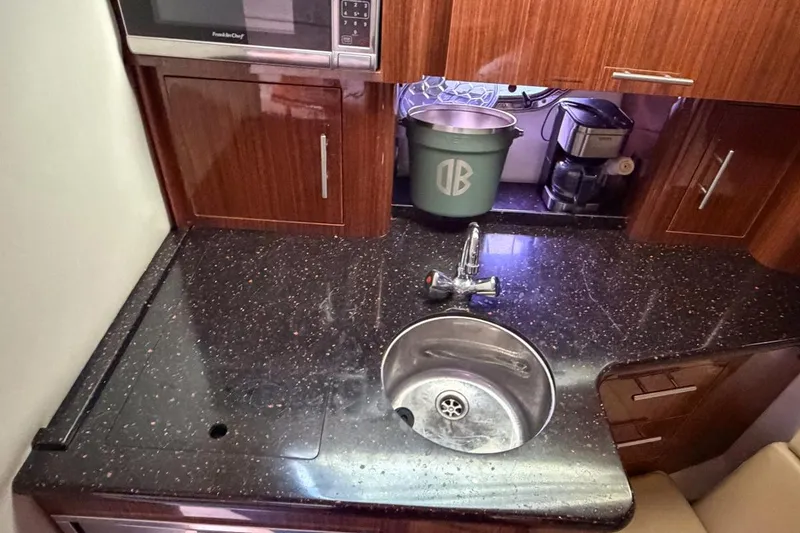 Slide: The Image of 2015 Regal 38 Express yacht kitchen with sink, microwave, and wooden cabinetry. - 100
