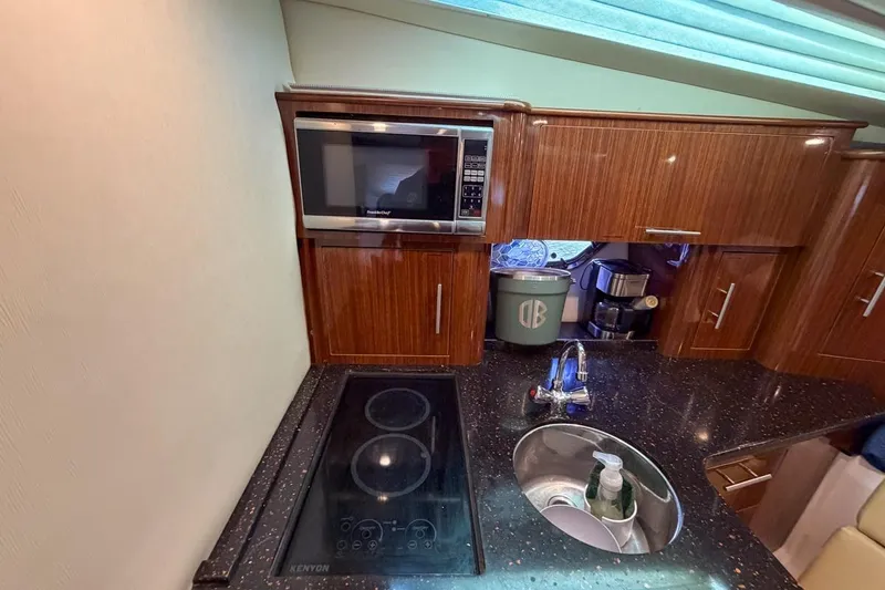 Slide: The Image of 2015 Regal 38 Express yacht kitchen with microwave, stove, and sink. - 99