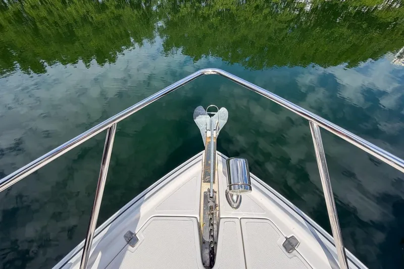 Slide: The Image of Bow view of 2015 Regal 38 Express boat on calm water reflecting trees. - 27