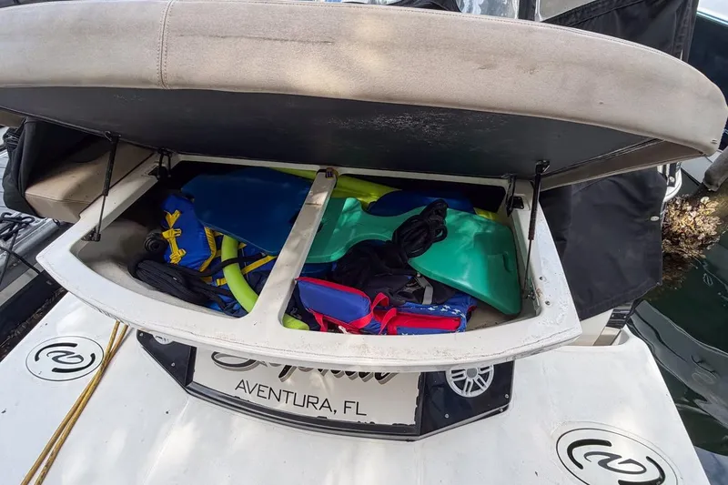Slide: The Image of Open storage compartment on 2015 Regal 38 Express boat, filled with water sports gear. - 14
