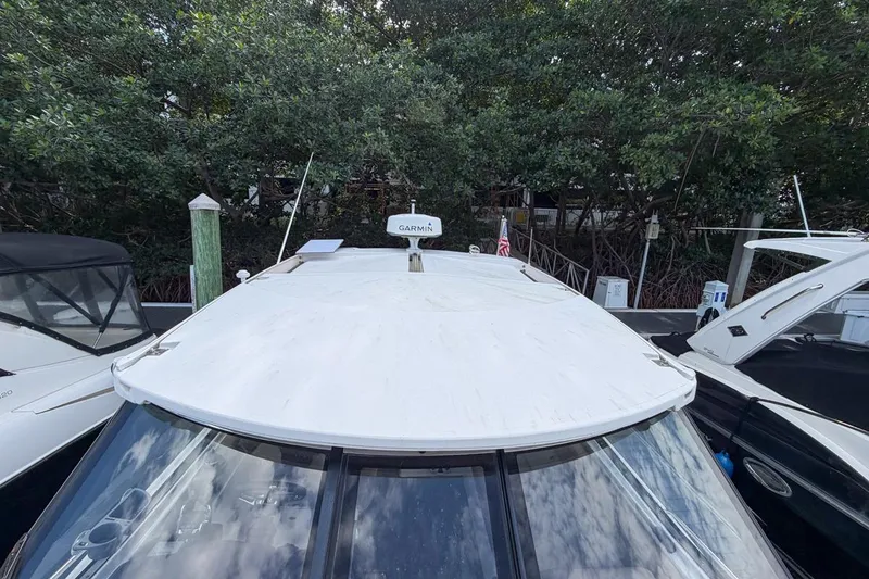 Slide: The Image of 2015 Regal 38 Express boat docked, featuring a white roof and Garmin equipment. - 42