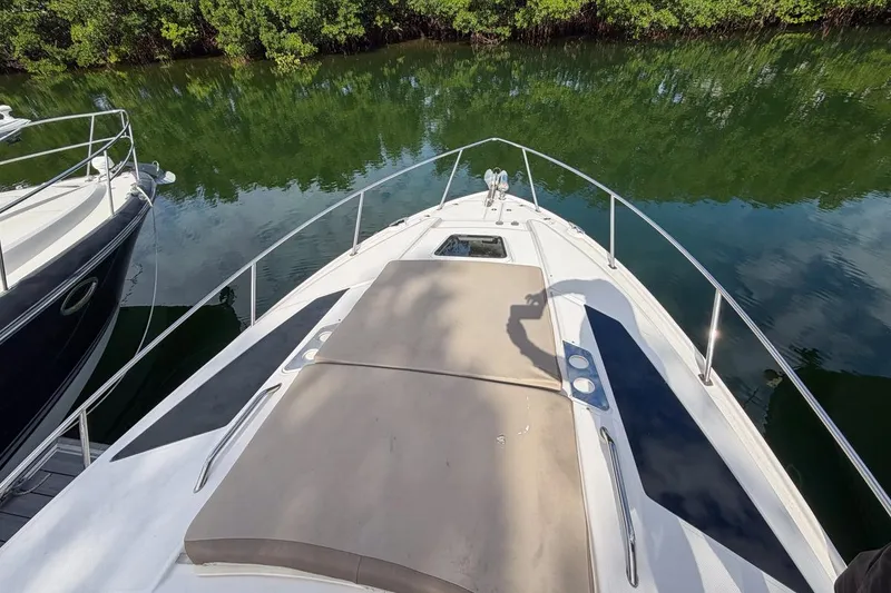 Slide: The Image of 2015 Regal 38 Express yacht bow view, docked near lush greenery. - 24