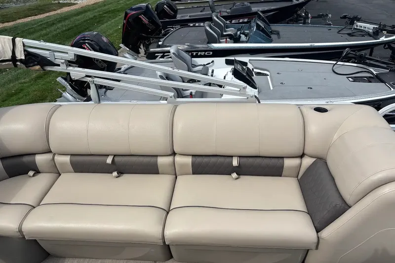 Slide: The Image of 2021 Sun Tracker Party Barge 22 with beige seating, parked near other boats. - 17