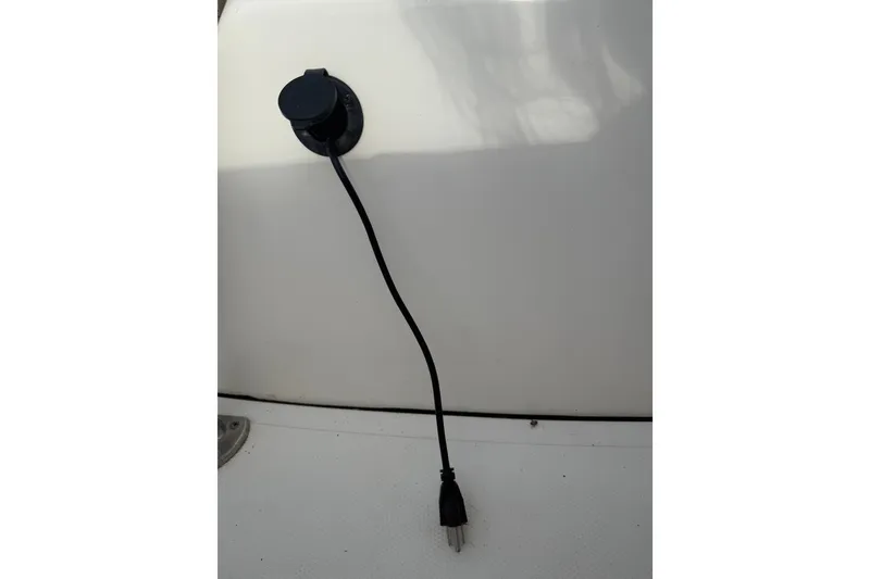 Slide: The Image of Un cable negro cuelga de un enchufe en la pared blanca del barco. - 21