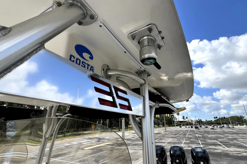 Slide: The Image of 2007 Wellcraft 35 Scarab Sport Open boat detail with Costa logo, parked under a blue sky. - 104