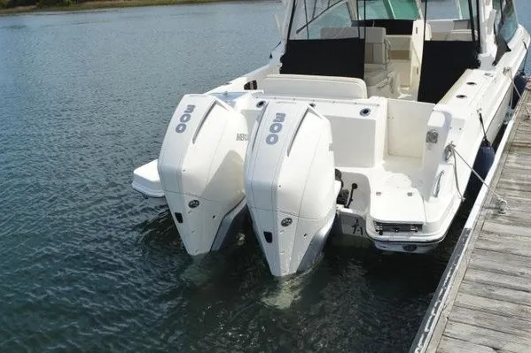 Slide: The Image of 2022 Boston Whaler 280 Vantage boat with dual outboard engines docked on calm water. - 3