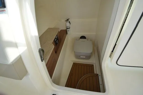 Slide: The Image of 2022 Boston Whaler 280 Vantage boat interior with compact toilet and wooden flooring. - 26