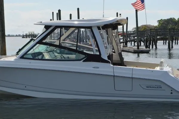 Slide: The Image of 2022 Boston Whaler 280 Vantage boat docked near a pier with American flag. - 16