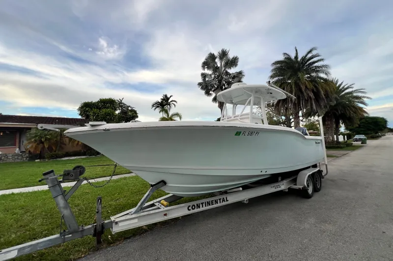 Slide: The Image of 2015 Tidewater 250 CC Adventure boat on trailer, parked near palm trees. - 2