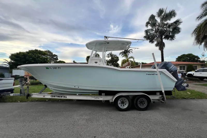 Slide: The Image of 2015 Tidewater 250 CC Adventure boat on trailer, parked outdoors with palm trees. - 3