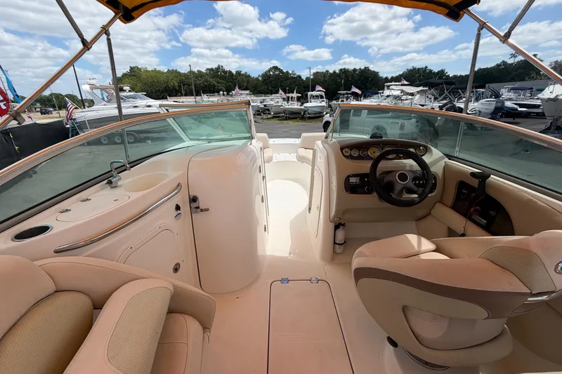 Slide: The Image of 2006 Chaparral Sunesta 236 boat interior with steering wheel and seating under a sunny sky. - 22