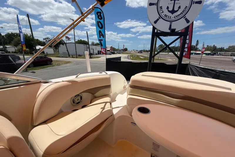 Slide: The Image of 2006 Chaparral Sunesta 236 boat interior with beige seating and table, outdoor dealership setting. - 89