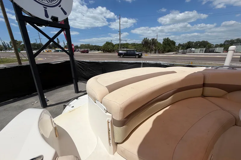 Slide: The Image of 2006 Chaparral Sunesta 236 boat with beige seating, parked near a road under a blue sky. - 92