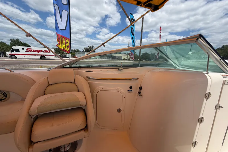 Slide: The Image of 2006 Chaparral Sunesta 236 boat interior with beige seating and windshield under blue sky. - 38