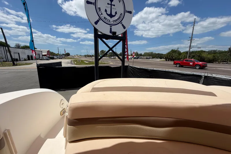 Slide: The Image of 2006 Chaparral Sunesta 236 boat interior with beige seating, parked near a road under a blue sky. - 91