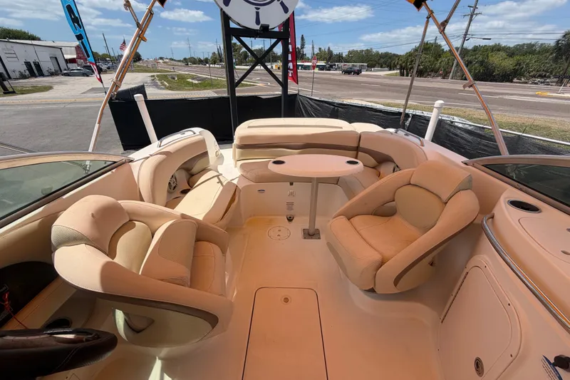 Slide: The Image of 2006 Chaparral Sunesta 236 boat interior with beige seating and table, parked outdoors. - 75