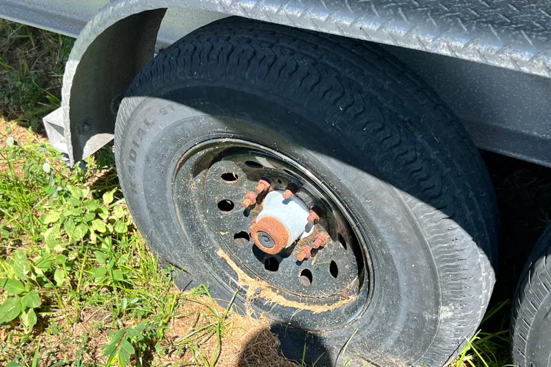 Slide: The Image of Rusty trailer wheel on grass, associated with 2006 Grady-White Express 330 boat. - 72