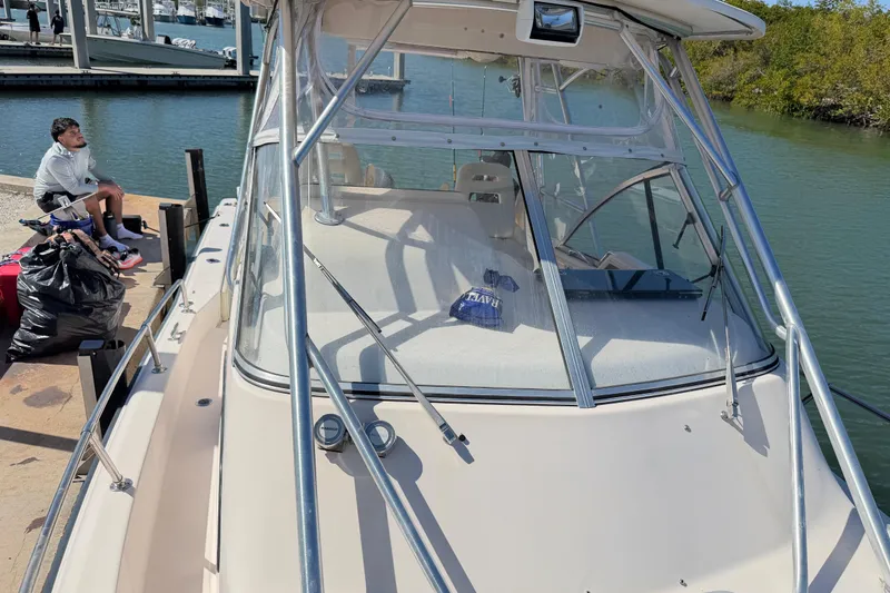 Slide: The Image of 2006 Grady-White Sailfish 282 docked, with a person sitting nearby on the pier. - 180