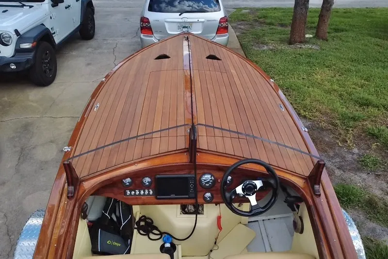 Slide: The Image of Custom Line 17 boat, 2025 model, with wooden deck and modern dashboard, parked near vehicles. - 16