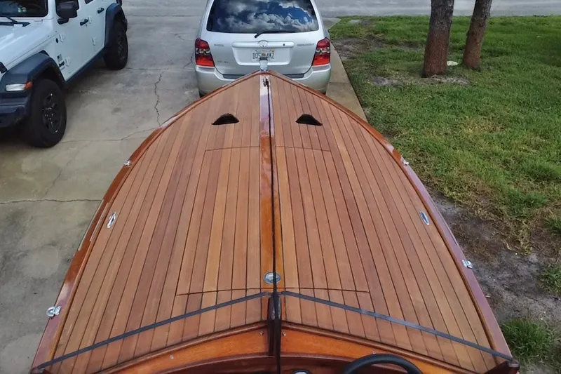 Slide: The Image of Wooden deck of a 2025 Custom Line 17 boat, parked near vehicles. - 15