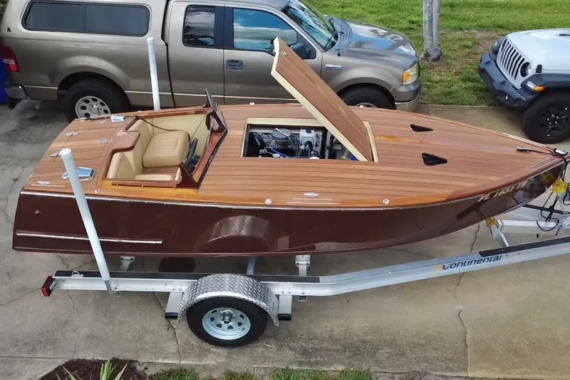Slide: The Image of Custom Line 17 boat, 2025 model, on trailer with open engine hatch, parked beside vehicles. - 22