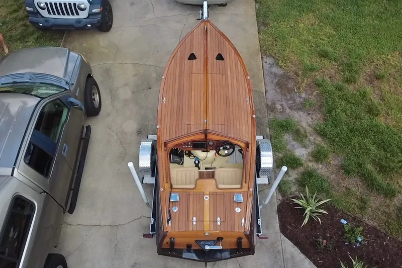 Slide: The Image of Overhead view of a 2025 Custom Line 17 wooden boat on a trailer, parked beside vehicles. - 7