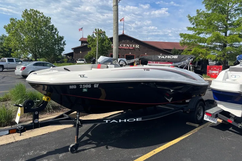 The Image of 2024 Tahoe T16 boat on trailer in parking lot, near a rustic building. - 0