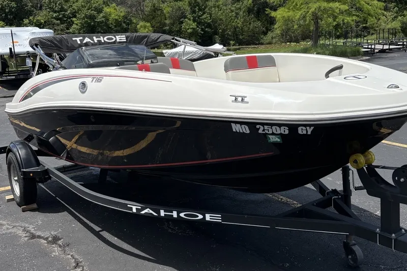 Slide: The Image of 2024 Tahoe T16 boat on trailer, parked outdoors with trees in background. - 4
