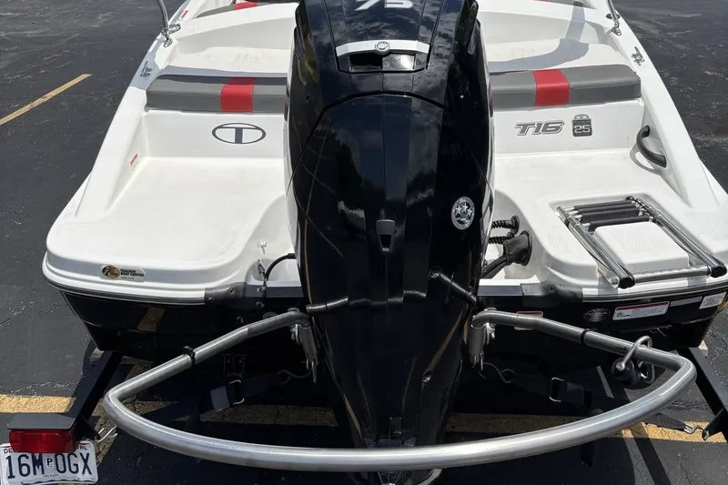 Slide: The Image of 2024 Tahoe T16 boat with outboard motor and swim platform in a parking lot. - 2
