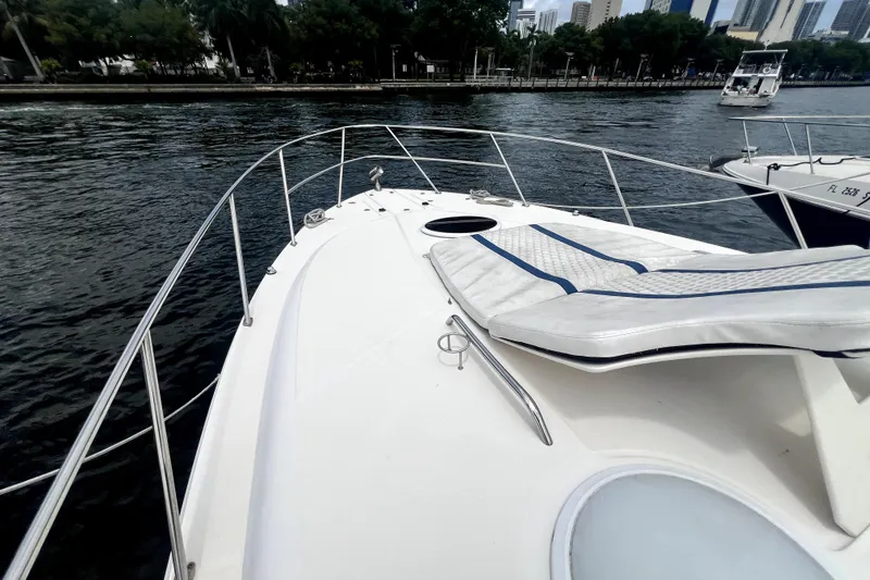 Slide: The Image of 2006 Regal Commodore 3560 IB yacht bow with sunpad, docked by a scenic waterfront. - 18