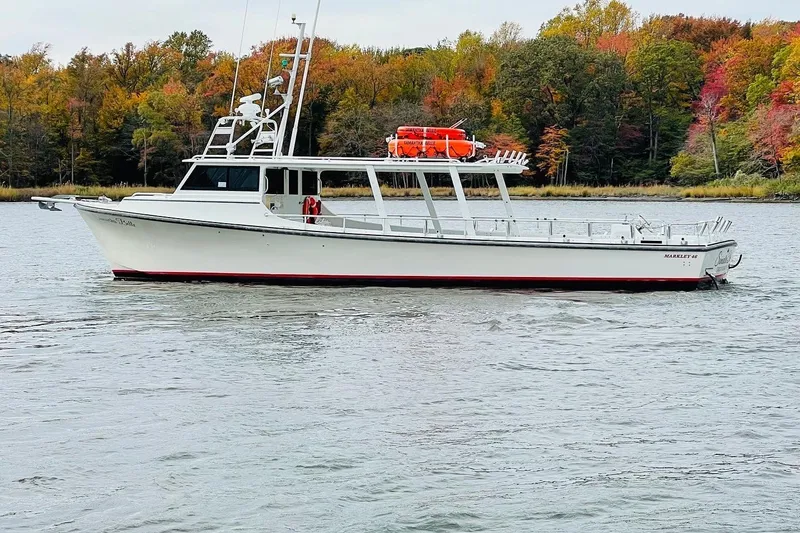 Slide: The Image of 1999 Markley 46 Chesapeake boat on water, surrounded by autumn trees. - 1