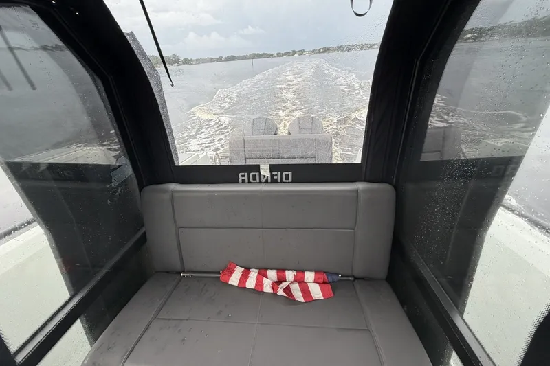 Slide: The Image of Interior view of 2023 XO DFNDR 9 boat with gray seating and American flag. - 8