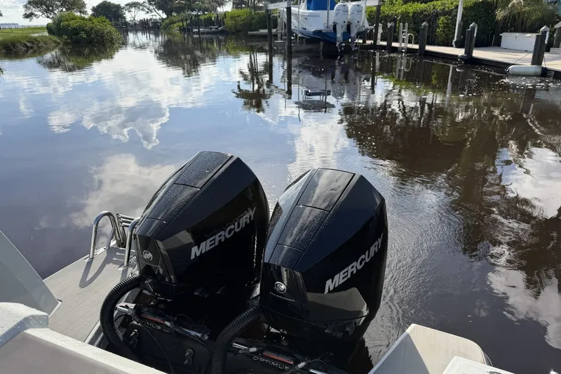 Slide: The Image of Twin Mercury outboard engines on a 2023 XO DFNDR 9 boat, docked by a serene waterway. - 21