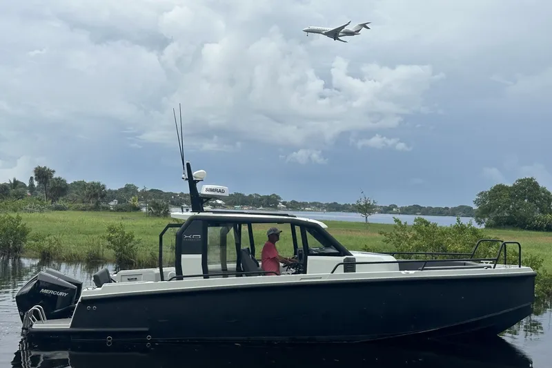 The Image of 2023 XO DFNDR 9 boat on water with airplane flying overhead. - 1