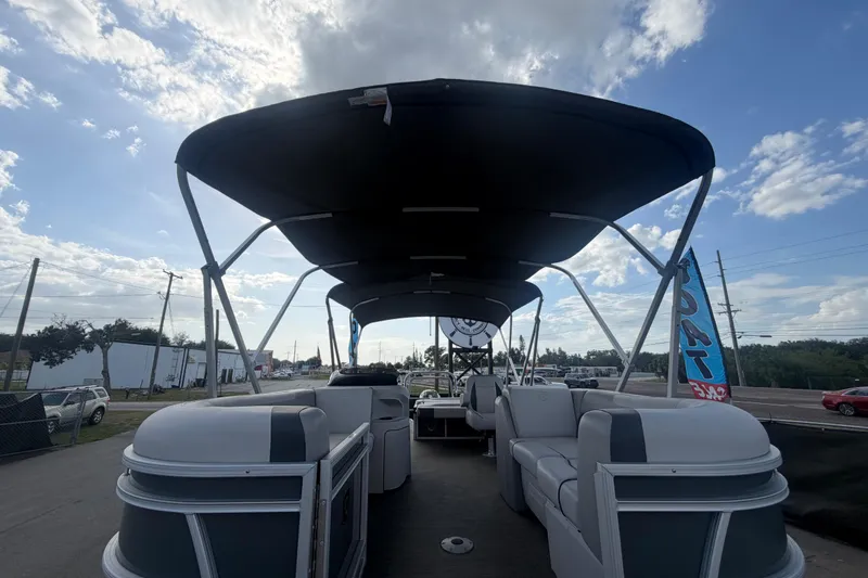 Slide: The Image of 2025 Godfrey Sweetwater 2286 SFL pontoon boat with canopy, parked outdoors under a cloudy sky. - 14