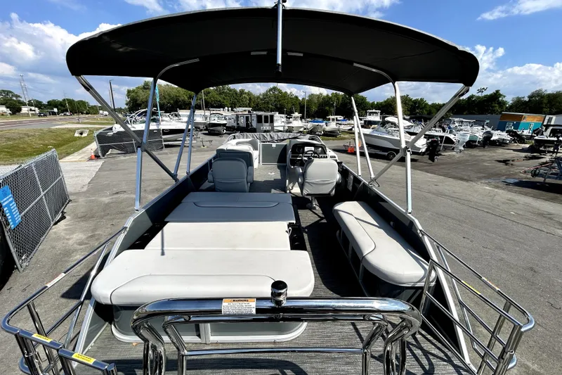 Slide: The Image of 2025 Godfrey Sweetwater 2286 SFL pontoon boat with canopy, parked in a marina. - 22