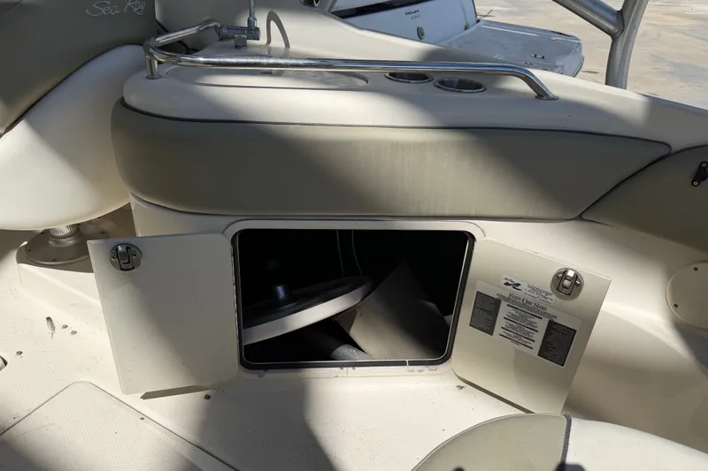 Slide: The Image of 2006 Sea Ray 240 Sundeck interior storage compartment with open door and seating area. - 31