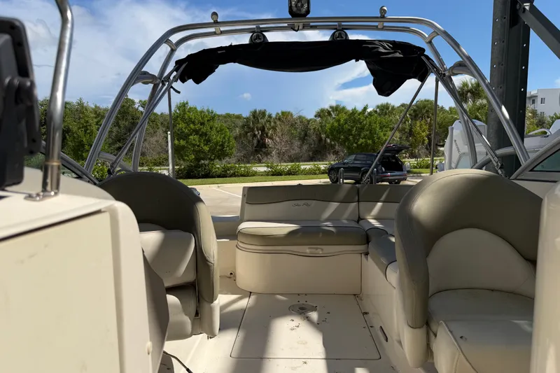 Slide: The Image of 2006 Sea Ray 240 Sundeck interior with seating and canopy, parked outdoors. - 15