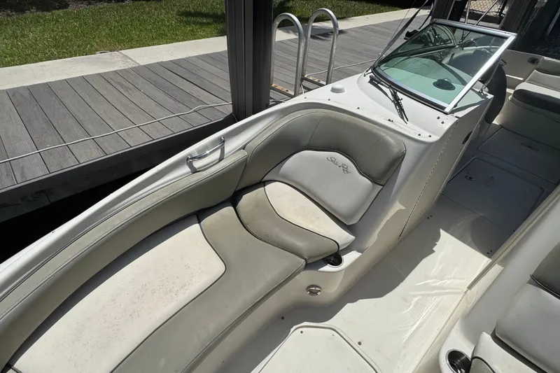 Slide: The Image of 2006 Sea Ray 240 Sundeck boat interior with cushioned seating and dockside view. - 9