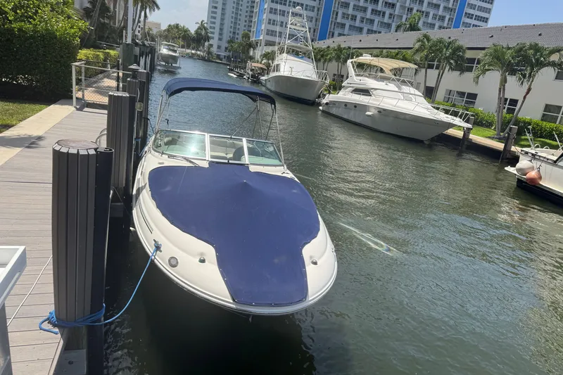The Image of 2006 Sea Ray 240 Sundeck docked in a sunny marina canal. - 2