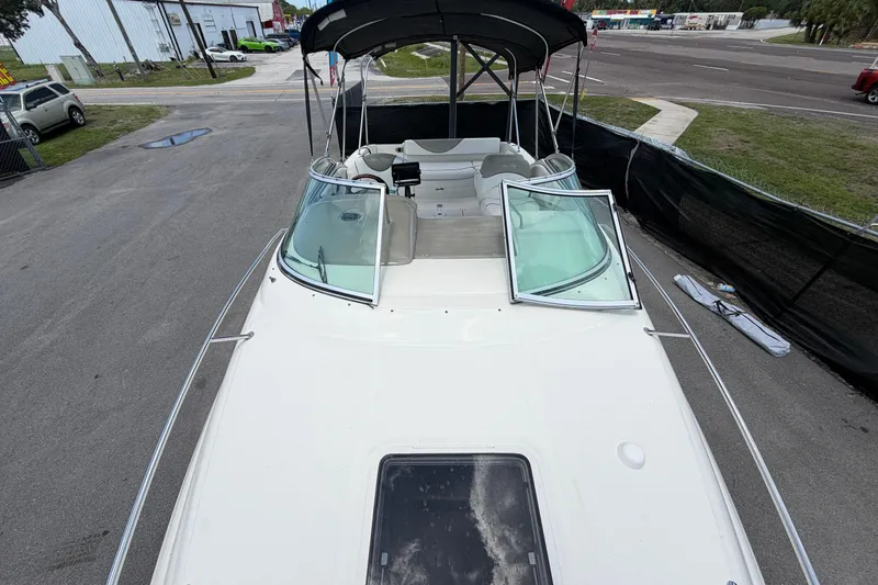 Slide: The Image of 2006 Sea Ray 250 Amberjack boat with open deck and windshield, parked on pavement. - 53