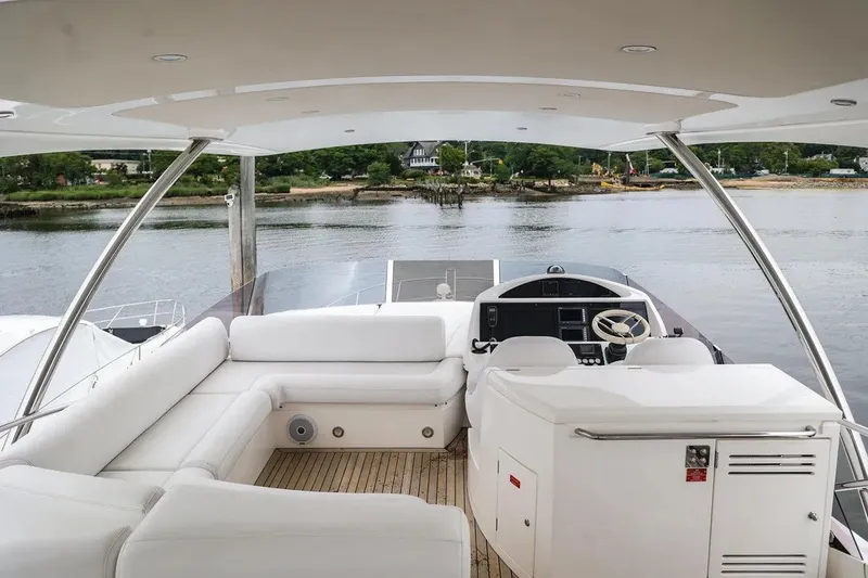 Slide: The Image of Luxurious 2016 Sunseeker Manhattan 65 yacht interior with white seating and helm, overlooking serene water. - 20