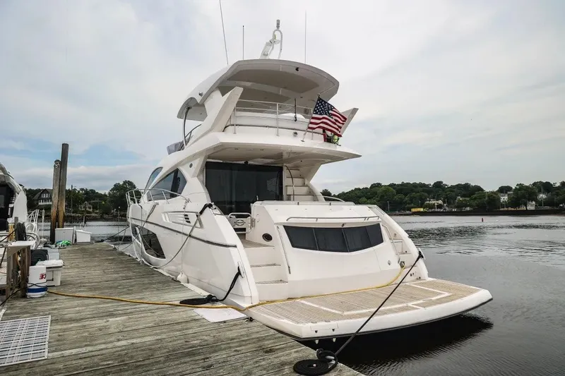 Slide: The Image of 2016 Sunseeker Manhattan 65 yacht docked at a marina, rear view with American flag. - 27