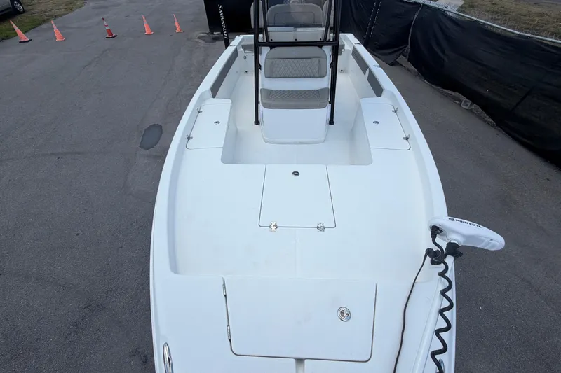 Slide: The Image of 2025 Savannah 210X boat deck with seating and trolling motor, parked on pavement. - 42