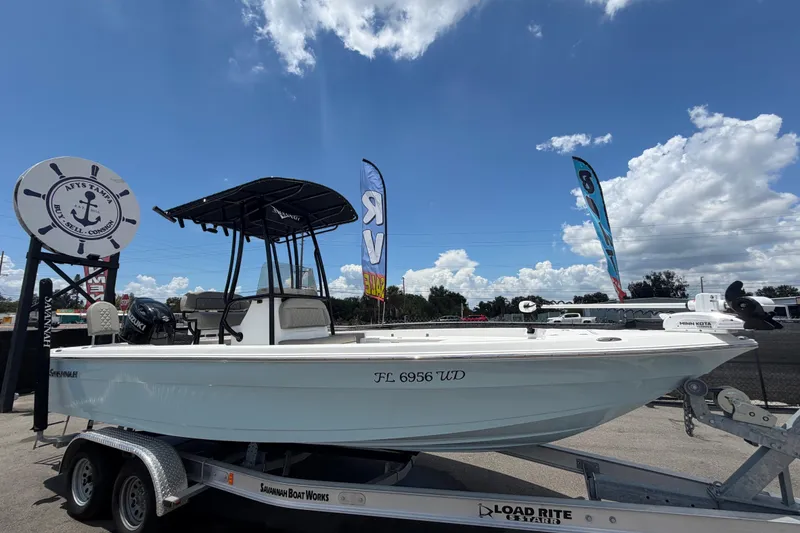 Slide: The Image of 2025 Savannah 210X boat on trailer under clear blue sky at dealership. - 1