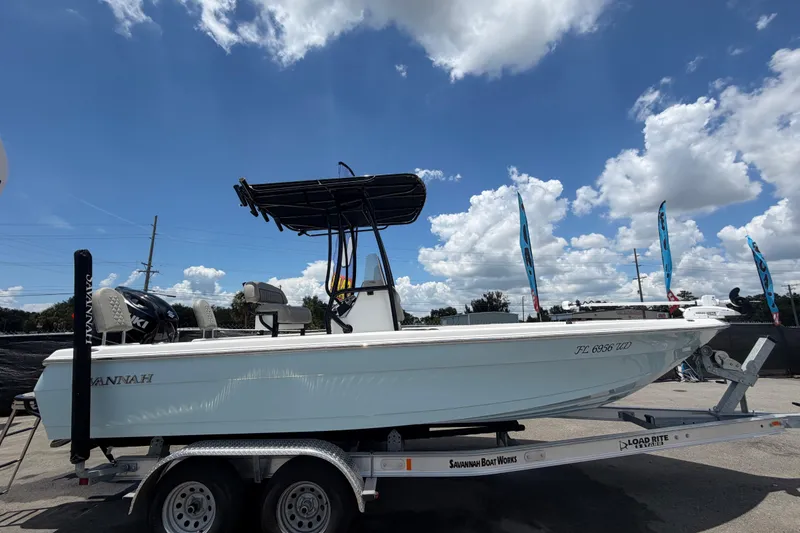 Slide: The Image of 2025 Savannah 210X boat on trailer under blue sky with clouds. - 2