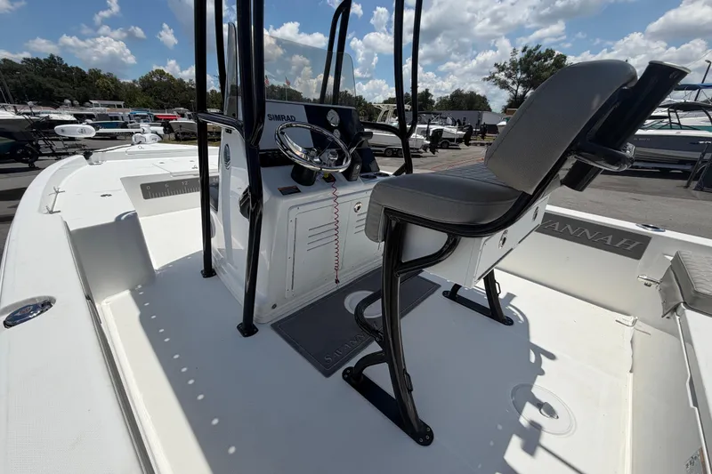 Slide: The Image of 2025 Savannah 210X boat interior with steering console and seating under a sunny sky. - 14